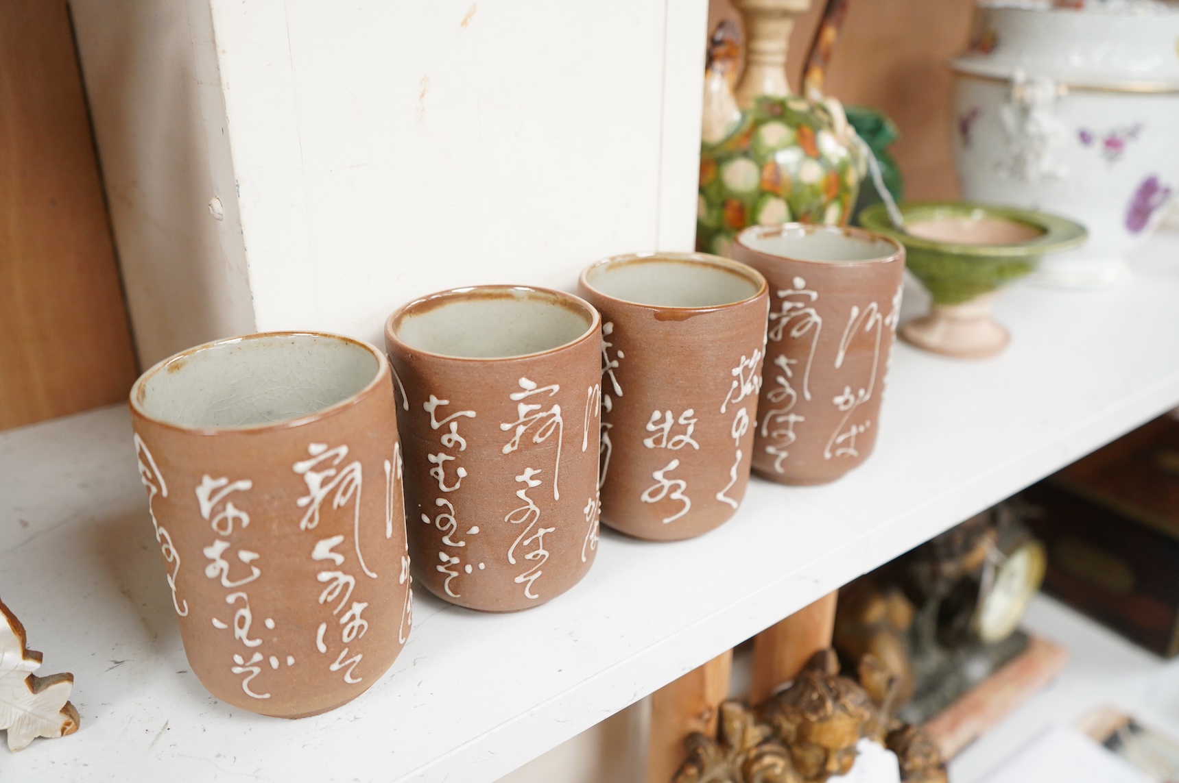 A set of four Japanese studio pottery beakers with calligraphy, 11cm high
